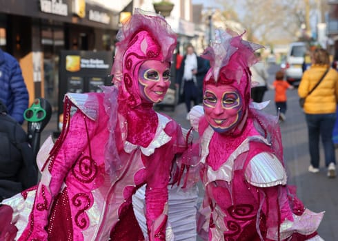 Noordwijkerhout, Netherlands - April 21, 2023: Women in pink fairy tale costumes on the street in Noordwijkerhout before the evening illuminated Flower Parade Bollenstreek