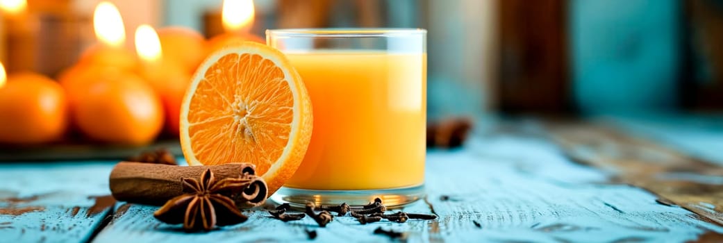 A glass of orange juice with fresh oranges, cinnamon, and warm candlelight. Copy space