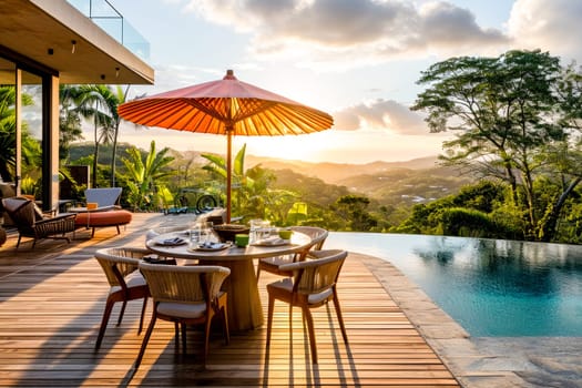 A luxurious poolside dining area with a stunning sunset view over a lush landscape. Copy space