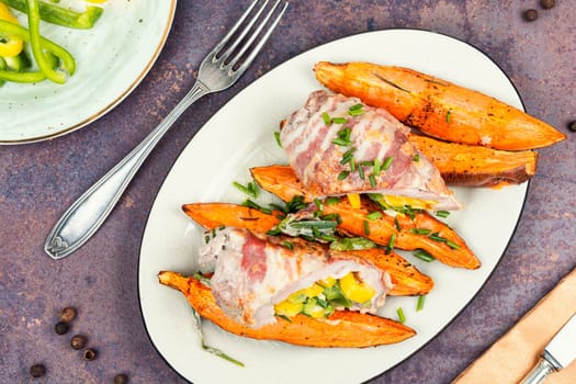 Roasted pork shoulder and sweet potatoes. Roulade with bacon and vegetables. Flat lay.