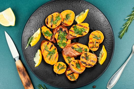 Grilled sweet potato, batata with olive oil and herbs. Copy space.