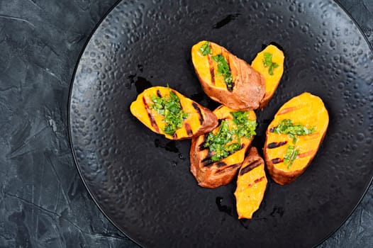 Grilled sweet potato, batata with olive oil and herbs. Copy space.
