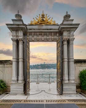 Sunset shot of Marble gate with decorated open door leading to the Bosphorus Strait, located at Beylerbeyi Palace, Istanbul, Turkey. Text above translate: In the name of God