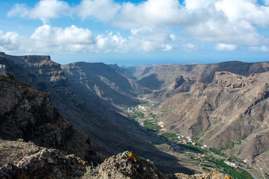Mountains with a small village in the valley on the Canary Island of Gran Canaria in Spain, with blue sky and clouds