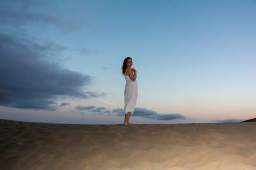 Young woman stands with her back in the sand dunes