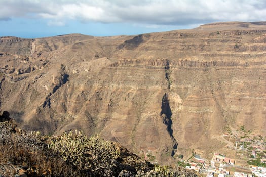 Mountains with a small village in the valley on the Canary Island of Gran Canaria in Spain, with blue sky and clouds