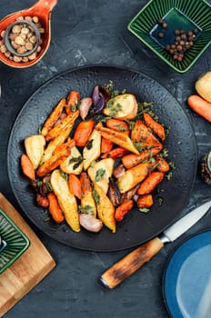 Winter vegan food of baked parsnip root and carrots. Roasted root vegetables.