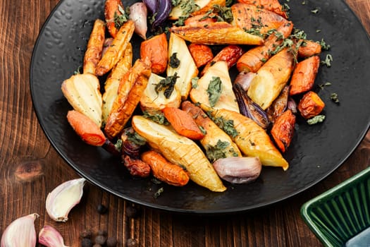 Winter vegan food of baked parsnip root and carrots. Roasted root vegetables.