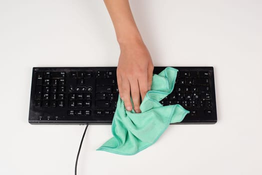 Cleaning computer keyboard in office with a wet wipe rag, dusty and dirty electronic, housework