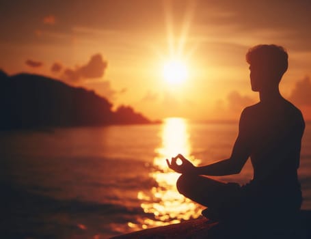 Silhouette of a young man in lotus position meditating on a serene beach against a sunset backdrop, evoking mindfulness and harmony