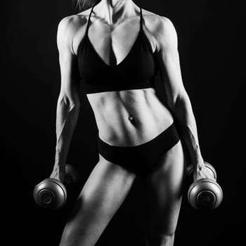 Sporty female doing exercise with a dumbbells, silhouette studio shot dark yellow background