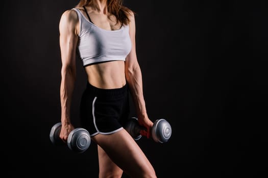 Sporty female doing exercise with a dumbbells, silhouette studio shot dark yellow background