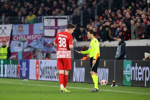 The assistant referee warns Michael Gregoritsch (SC Freiburg) to remain calm during the VAR review during the Europa League match - Round of 16: SC Freiburg vs West Ham United