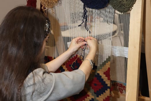 A lady making a rug by hand