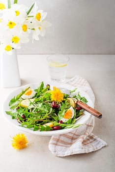Dandelion salad with eggs, potato and beans on bright table background closeup
