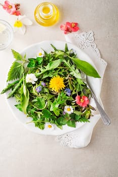 Spring salad with flowers, herbs and plants. Wild garlic, nettle, dandelion and other medicinal herbs and wild edible plants growing in early spring.
