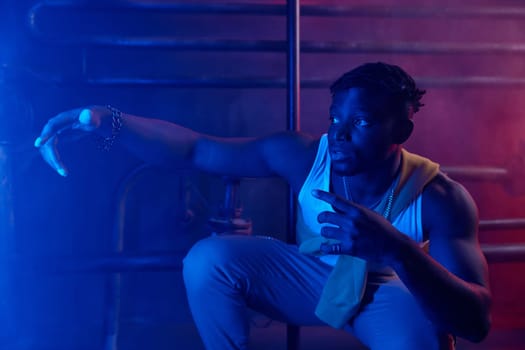 Young cool guy rapper posing for camera in neon light. Sportive millennial boy hip-hop dancer in stylish street style clothes portrait