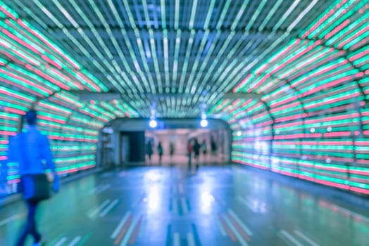 Blur abstract bokeh of colorful LED light tunnel with walking people