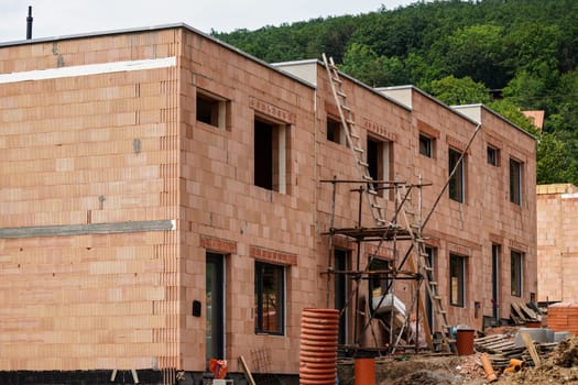 Small building construction site, wall made of orange bricks, small scaffolding near