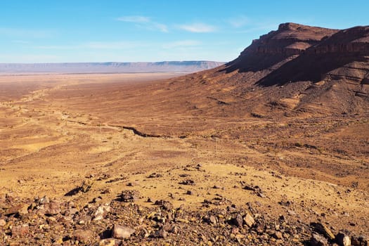 Flat large rocky canyon basin with clear sky above - typical landscape in Southern Morocco