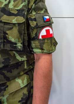 Brno, Czechia - October 08, 2021: Red cross sign and Czech flag on modern uniform sleeve of medic soldier, closeup detail