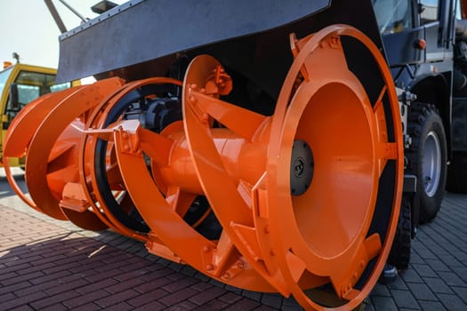 Bright orange rotary snow plough front displayed at military fair, closeup detail