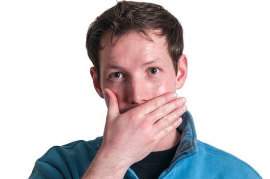 Frontal head portrait of a young brunette Caucasian man covering his mouth with his right hand and looking at the camera isolated on white.