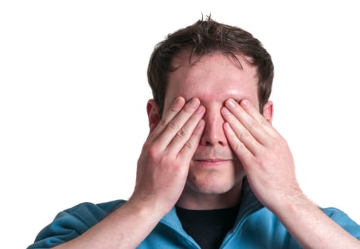 Frontal head portrait of a young brunette Caucasian man holding both hands over his eyes isolated on white.