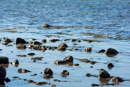 Big rock with stones lie in the water on the coast of the Baltic Sea