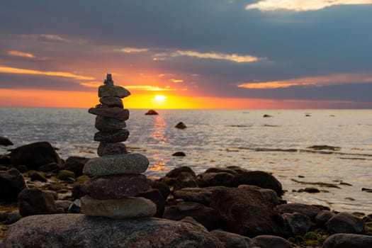 Stacked stones on a beach on the Baltic Sea coast at orange sunset