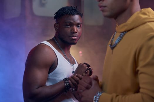 Portrait of cool high hop gangsters in dark city street. Serious rap singer wearing urban clothes and stylish accessories