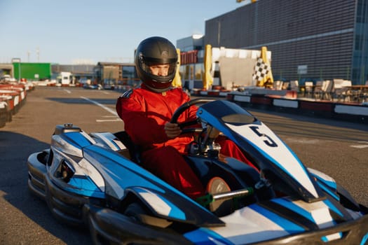 Go-cart racer moving fast on open air motor racing track. Extreme riding leisure activity, training at sports club