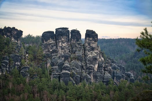 Rugged rocks on the Basteibridge. Wide view over trees and mountains. National park in Germany