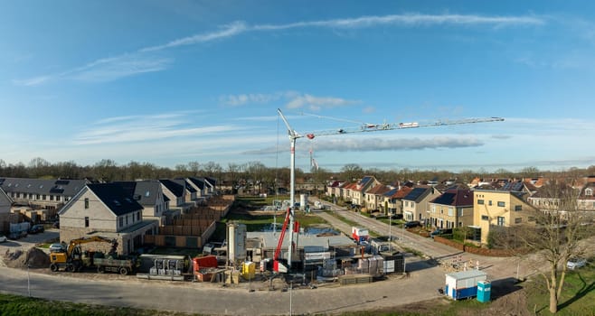 OLDENZAAL, NETHERLANDS - MARCH 2, 2024: Aerial shot of a constructioin site with large crane in a residential area