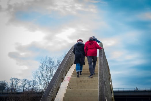 unknown couple climbing an outdoor stair crossing a canal