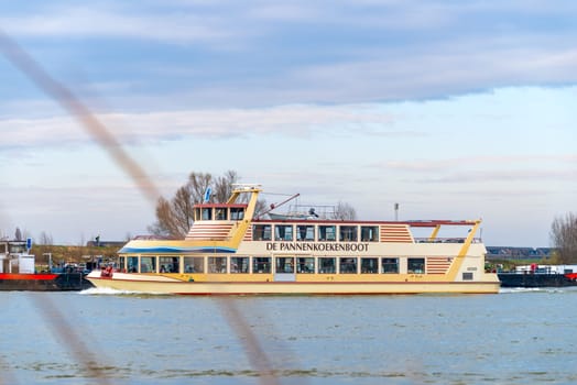 NIJMEGEN, NETHERLANDS - MARCH 9, 2024: Touristic boat called "De Pannenkoekenboot"" (the pancake boat) on the Waal River in the Netherlands."