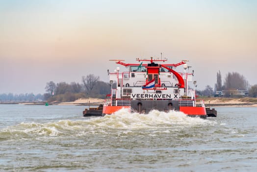 NIJMEGEN, NETHERLANDS - MARCH 9, 2024: Enormous dutch barge navigating the Waal river with a load of black sand