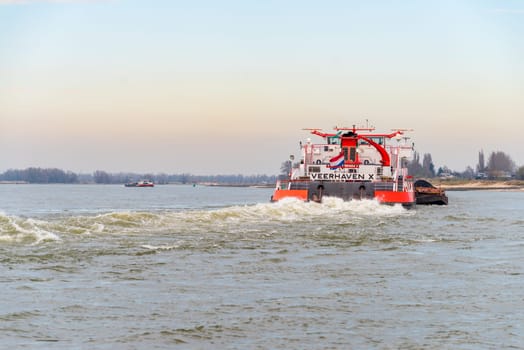 NIJMEGEN, NETHERLANDS - MARCH 9, 2024: Enormous dutch barge navigating the Waal river with a load of black sand