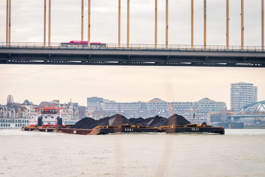 NIJMEGEN, NETHERLANDS - MARCH 9, 2024: Enormous dutch barge navigating the Waal river with a load of black sand