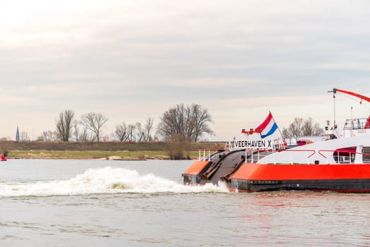 NIJMEGEN, NETHERLANDS - MARCH 9, 2024: Enormous dutch barge navigating the Waal river with a load of black sand