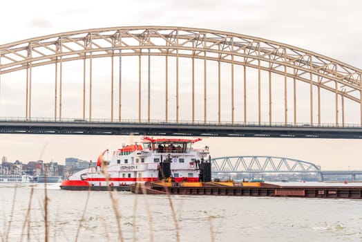 NIJMEGEN, NETHERLANDS - MARCH 9, 2024: Enormous dutch barge navigating the Waal river with a load of black sand