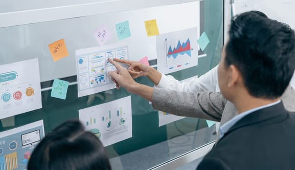 A man and a woman are looking at a board with graphs and numbers