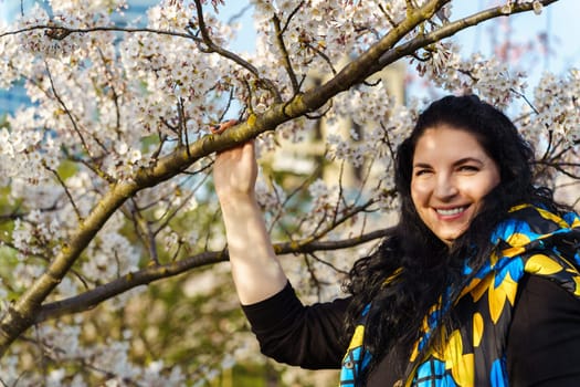 Attractive young ukrainian woman smiling in blooming cherry orchard in spring.
