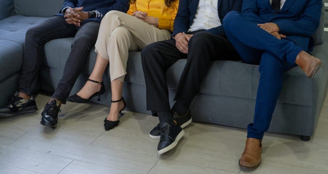 Four people are sitting on a couch, with one person wearing a yellow shirt. Concept of relaxation and camaraderie, as the group of people are comfortable enough to sit close together on the couch
