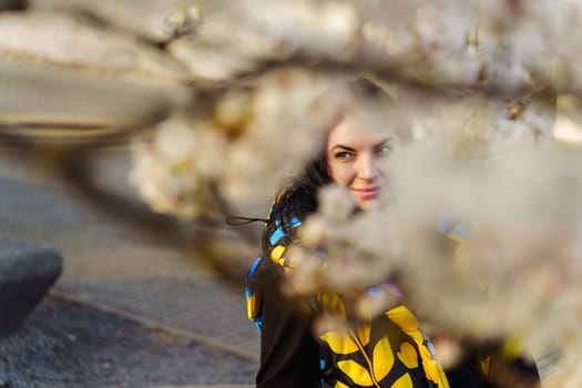 Attractive young brunette woman walking in spring in blooming cherry garden.