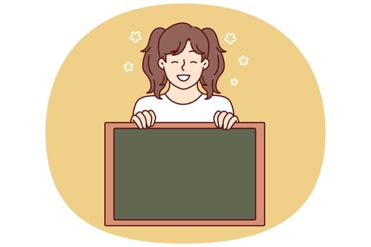 Little girl smiling demonstrates empty chalkboard designed for applying notifications or promotional offers. Preteen girl with advertising chalkboard advises to pay attention to space for text