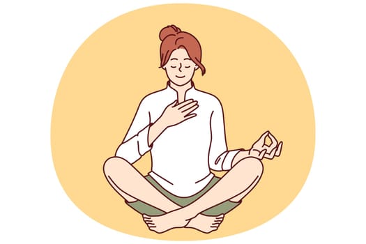 Woman meditates with hand on heart and wishes to heal herself through yoga and Buddhist spiritual practices. Girl sitting in lotus position takes care of heart chakra and relaxes during yoga