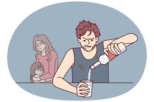 Drinking father sitting at table, pours vodka into glass, ignoring upset wife and little daughter. Alcoholic man with unshaven face drinks vodka, causing inconvenience to cohabitant and child