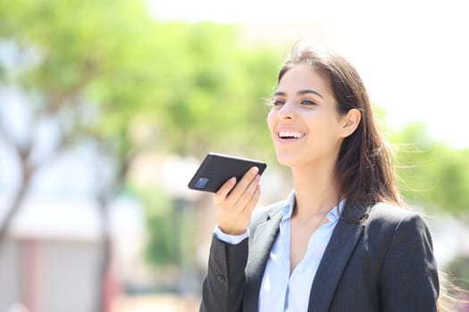 Happy executive dictating message on phone in the street