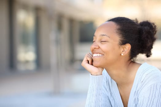Happy black woman relaxing sitting in a street